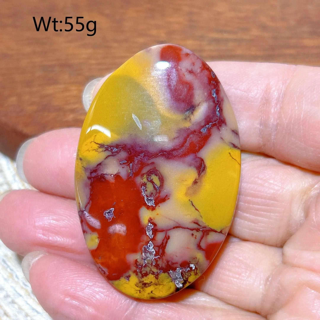 Smooth Mookaite Jasper palm stone featuring vibrant red, yellow, and cream swirls for grounding and vitality.