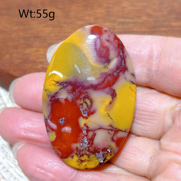 Smooth Mookaite Jasper palm stone featuring vibrant red, yellow, and cream swirls for grounding and vitality.