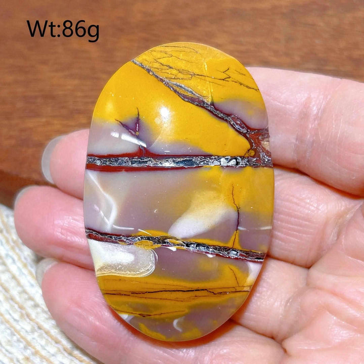 Smooth Mookaite Jasper palm stone featuring vibrant swirls of red, yellow, and mauve for grounding and vitality.