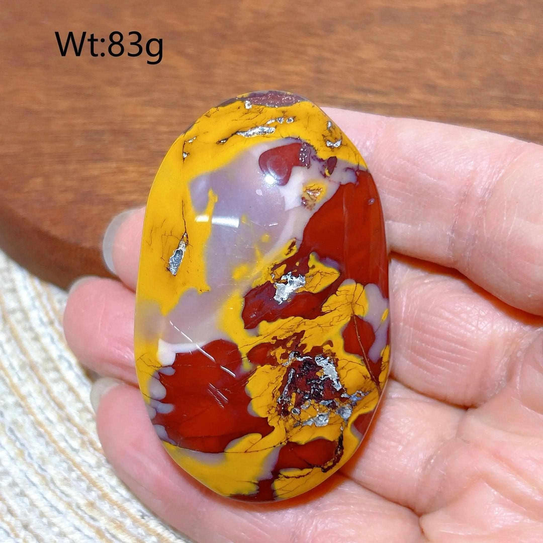 Smooth, polished Mookaite Jasper palm stone featuring vibrant swirls of red, yellow, and mauve for grounding energy.