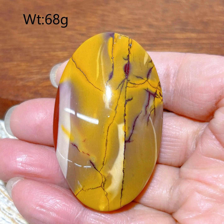 Smooth 68g Mookaite Jasper palm stone featuring vibrant swirls of mustard yellow, red, and cream for grounding energy.