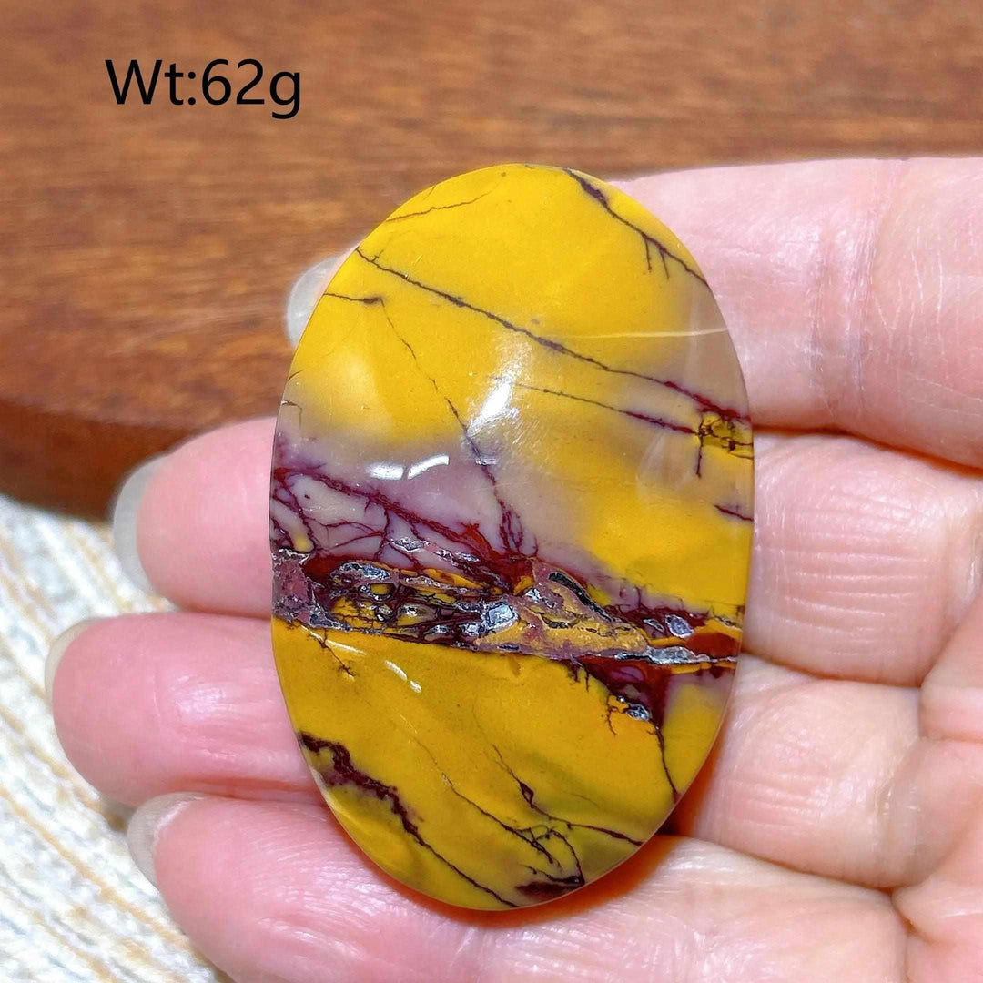 Smooth 62g Mookaite Jasper palm stone featuring vibrant mustard yellow, red, and cream swirls for grounding energy.