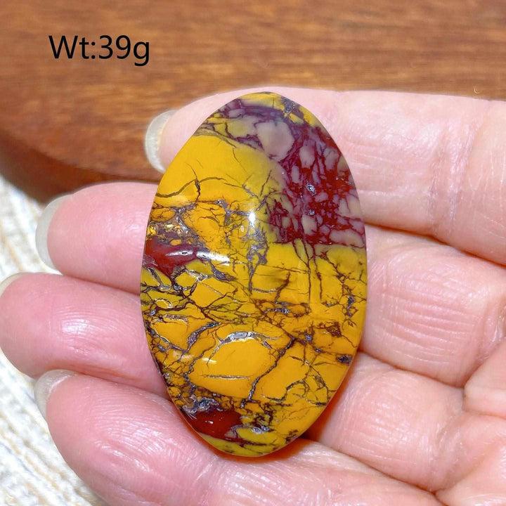 Smooth 39g Mookaite Jasper palm stone featuring vibrant red and mustard yellow swirls for grounding and vitality.