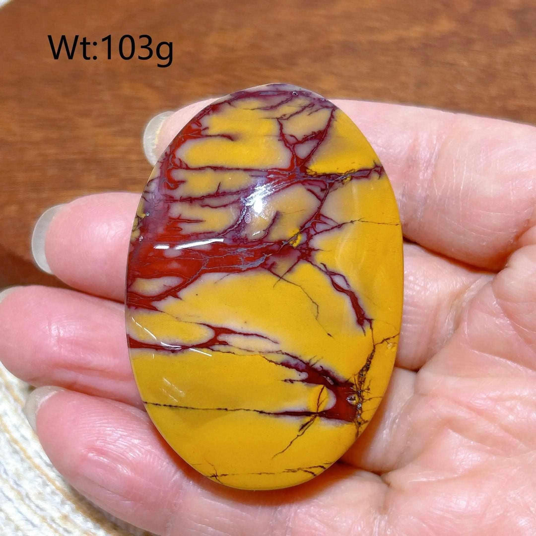Smooth 103g Mookaite Jasper palm stone featuring vibrant red and mustard yellow swirls for grounding and vitality.