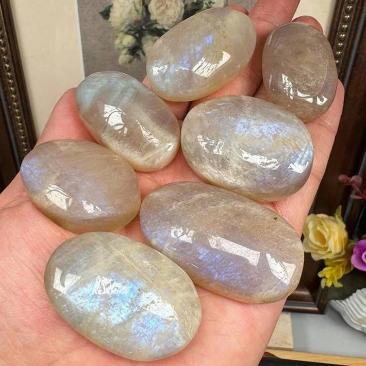 Hand-polished natural blue flash moonstone palm stones with glowing iridescent shimmer, perfect for healing and meditation.