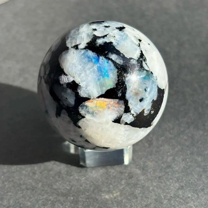 Polished Moonstone sphere featuring iridescent blue flashes and striking black matrix patterns, perfect for crystal healing.