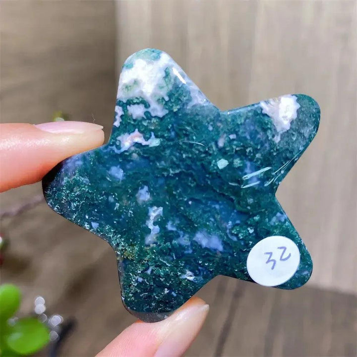 Hand-carved moss agate star crystal with deep green inclusions, promoting new beginnings and connection to nature.
