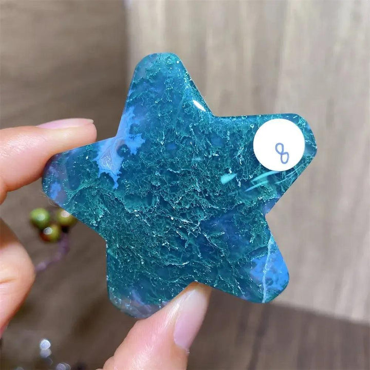 Hand-carved moss agate star crystal carving, showcasing deep green inclusions and vibrant blue hues for new beginnings.
