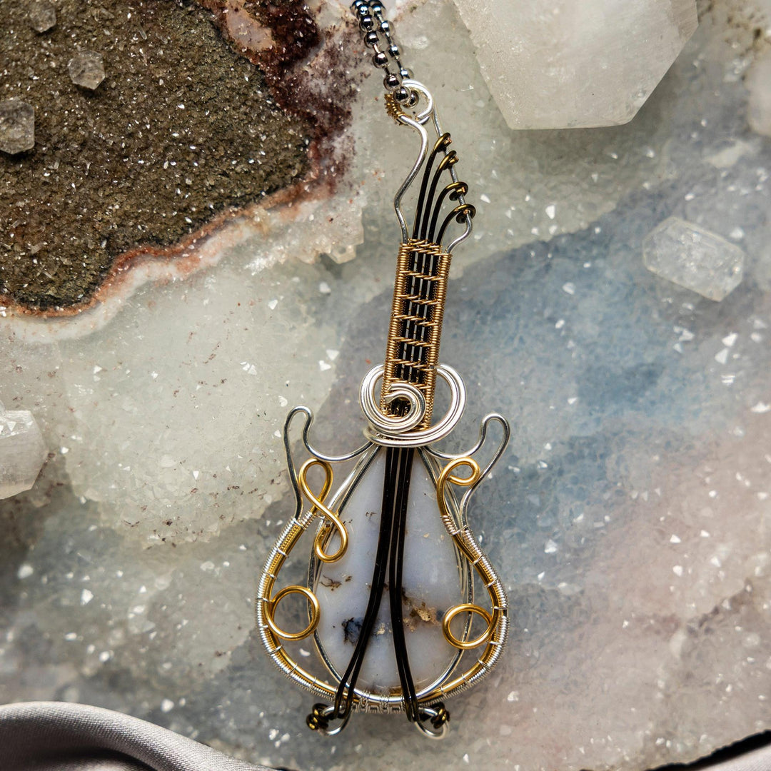 Moss Agate Guitar Wire Wrap Pendant: Handcrafted copper guitar with green moss-like inclusions, promoting new beginnings.