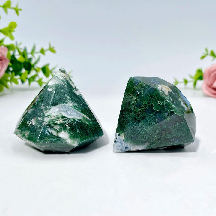 Two polished Moss Agate crystals in faceted diamond shapes, displaying green dendritic inclusions.