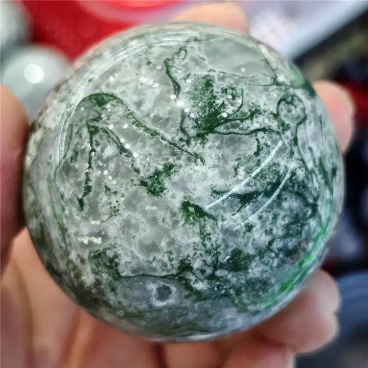 Moss Agate Sphere, a hand-polished, translucent crystal with vibrant green moss-like inclusions for abundance and new beginnings.