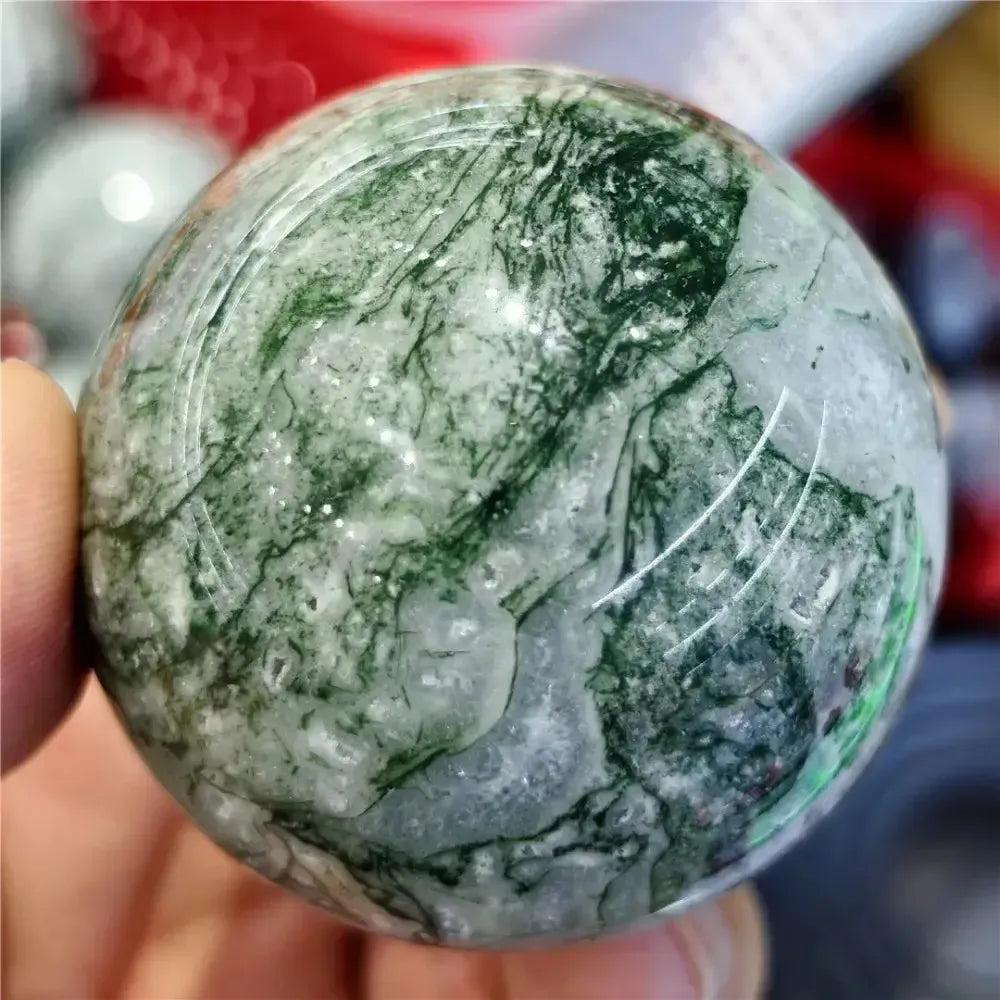 Moss Agate Sphere, a hand-polished crystal with vibrant green inclusions resembling moss and forest canopies.