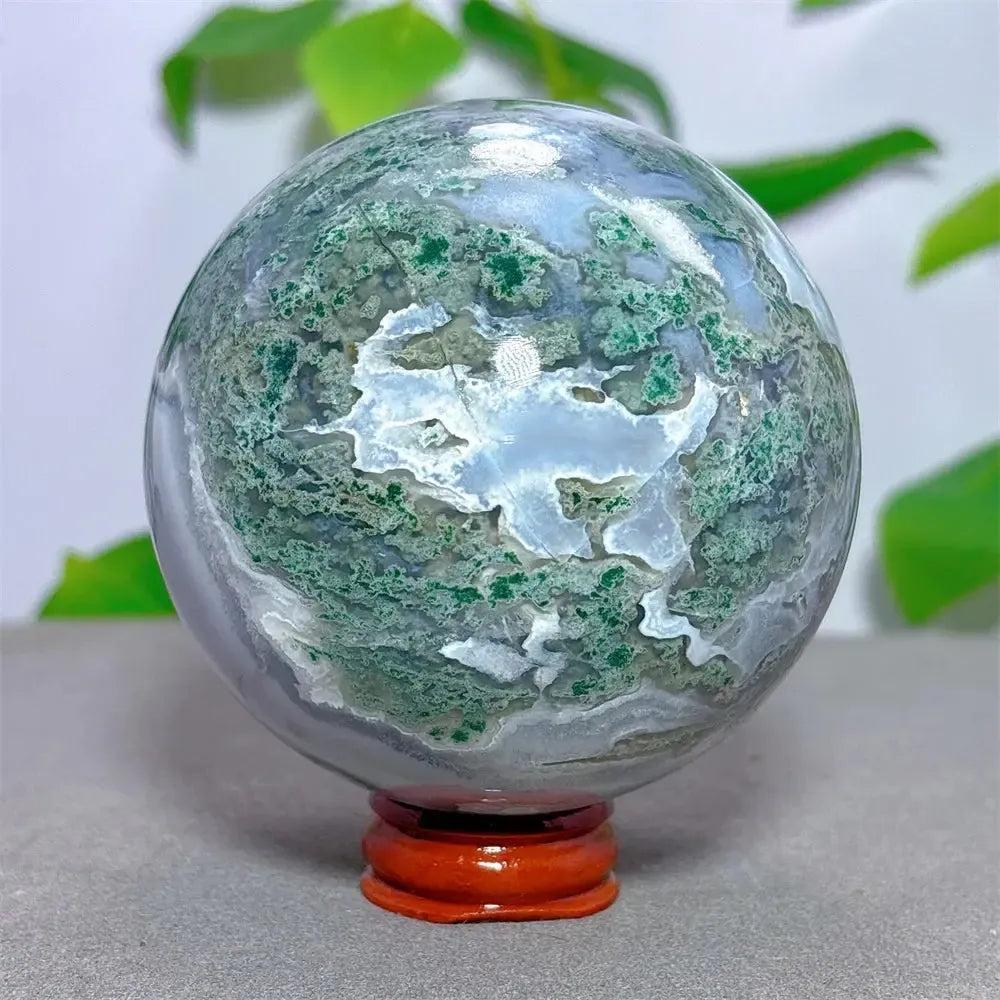 Moss Agate Sphere, 78mm, with vibrant green dendritic inclusions resembling a frozen landscape, on a wooden stand.