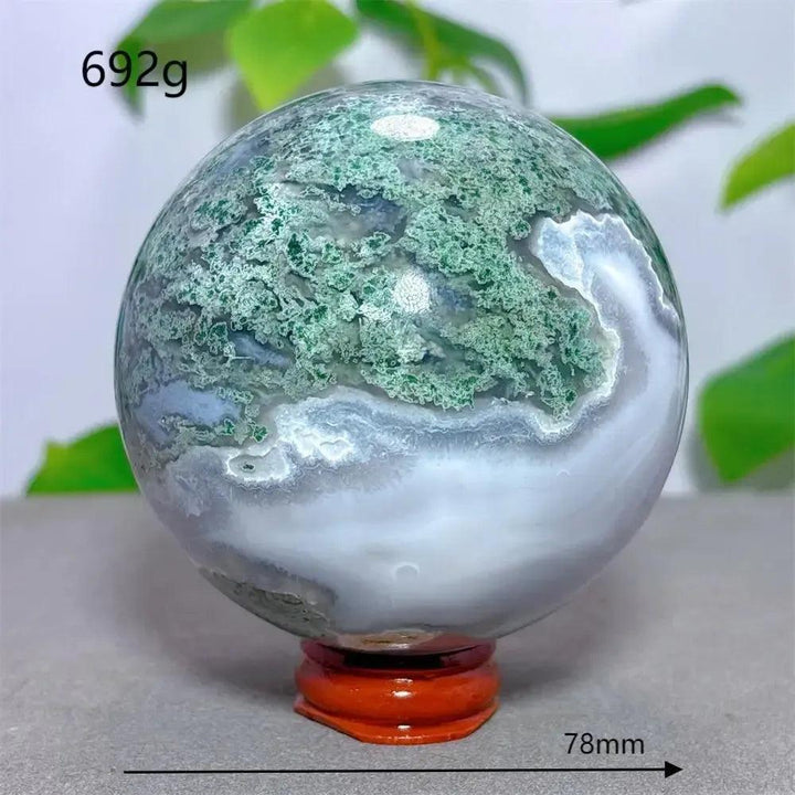 Moss Agate Sphere 78mm: Translucent chalcedony with green moss-like inclusions, hand-polished on a wooden stand.
