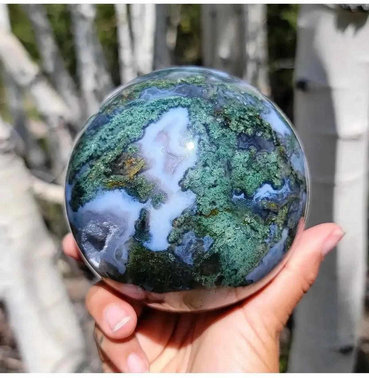 Hand-polished Moss Agate Crystal Sphere, showcasing lush green moss-like inclusions and milky quartz, promoting growth and abundance.