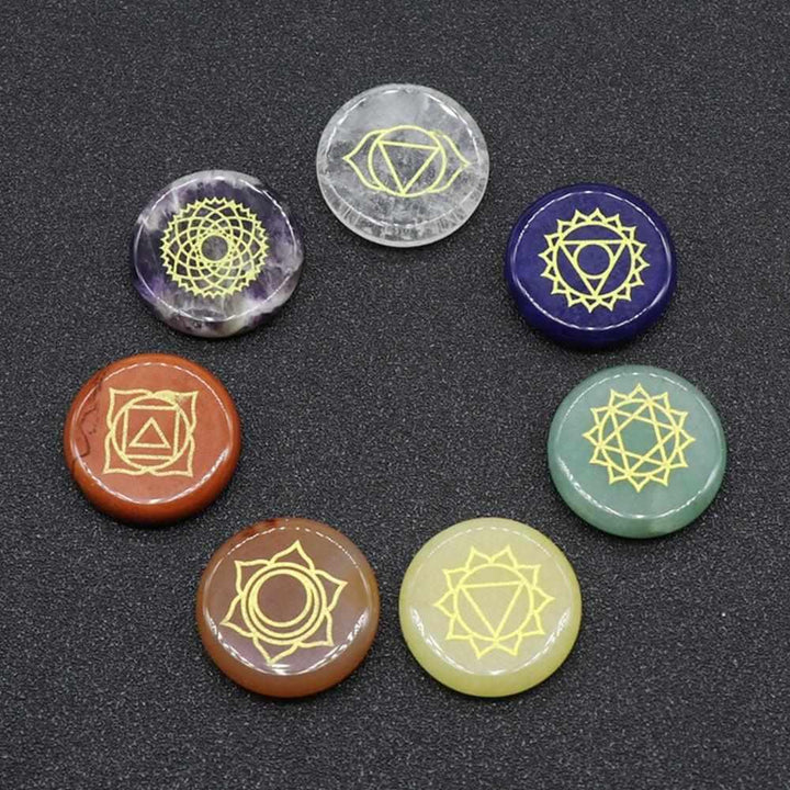 Seven 25mm polished crystal coins engraved with gold chakra symbols for meditation, energy balancing, and healing.
