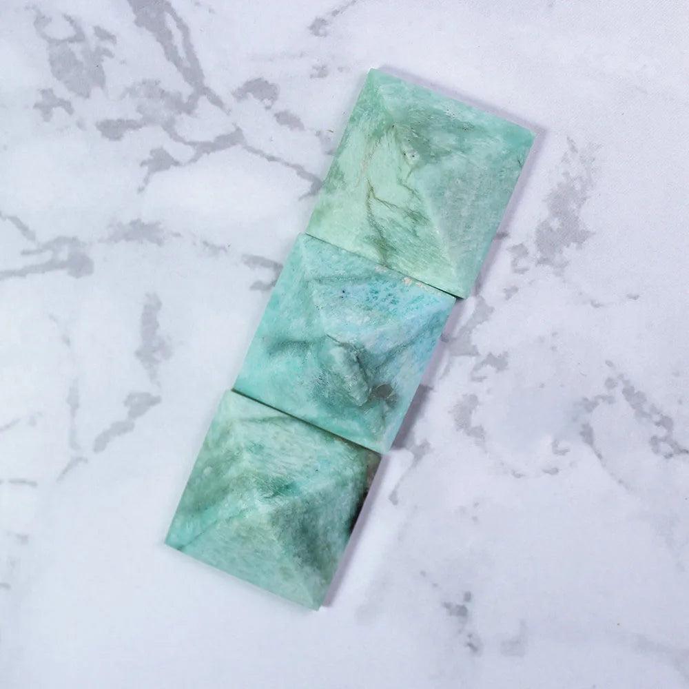 Natural Amazonite Crystal Pyramid for Healing and Calm. Three soft blue-green amazonite pyramids on marble.