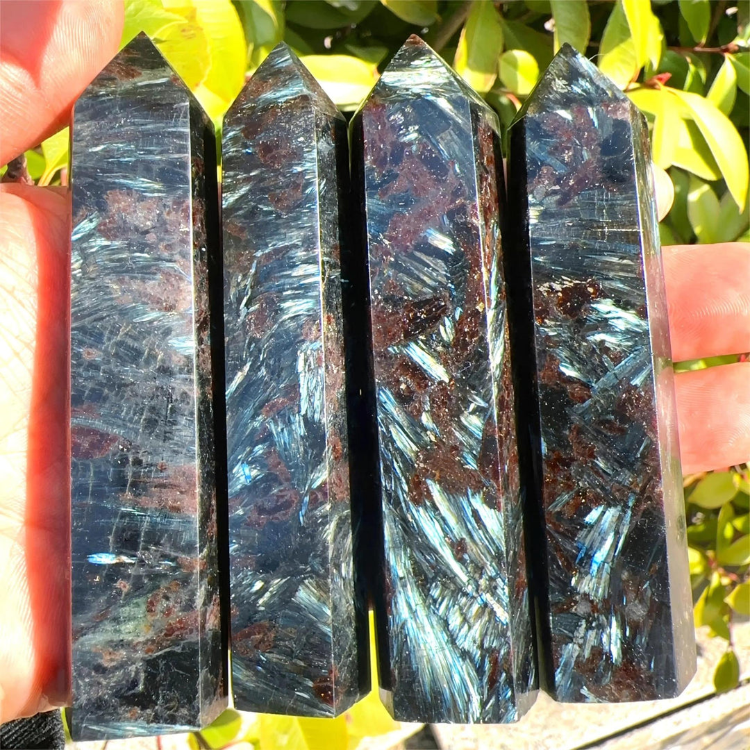 Four polished Natural Astrophyllite Towers with Arfvedsonite Flash, showcasing dark matrix, golden-bronze blades, and electric blue-green flashes.