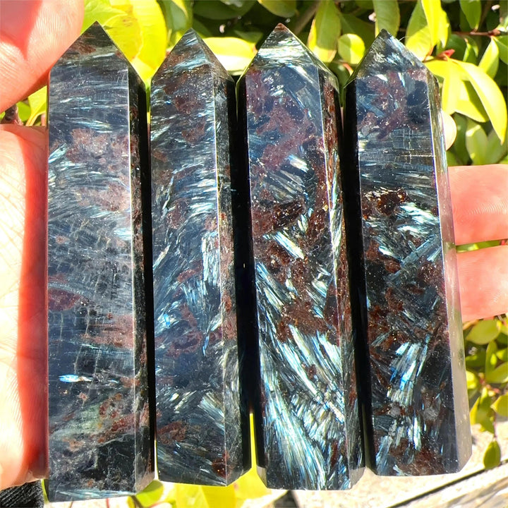 Four polished Natural Astrophyllite Towers with Arfvedsonite Flash, showcasing dark matrix, golden-bronze blades, and electric blue-green flashes.