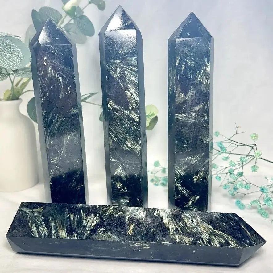 Polished astrophyllite towers with arfvedsonite flash, featuring dark matrix and metallic golden-bronze blades.
