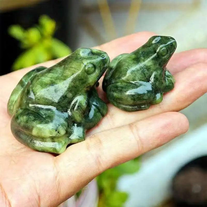 Two vibrant green Xiuyan Jade crystal frog figurines, symbolizing transformation and abundance, held in a palm.