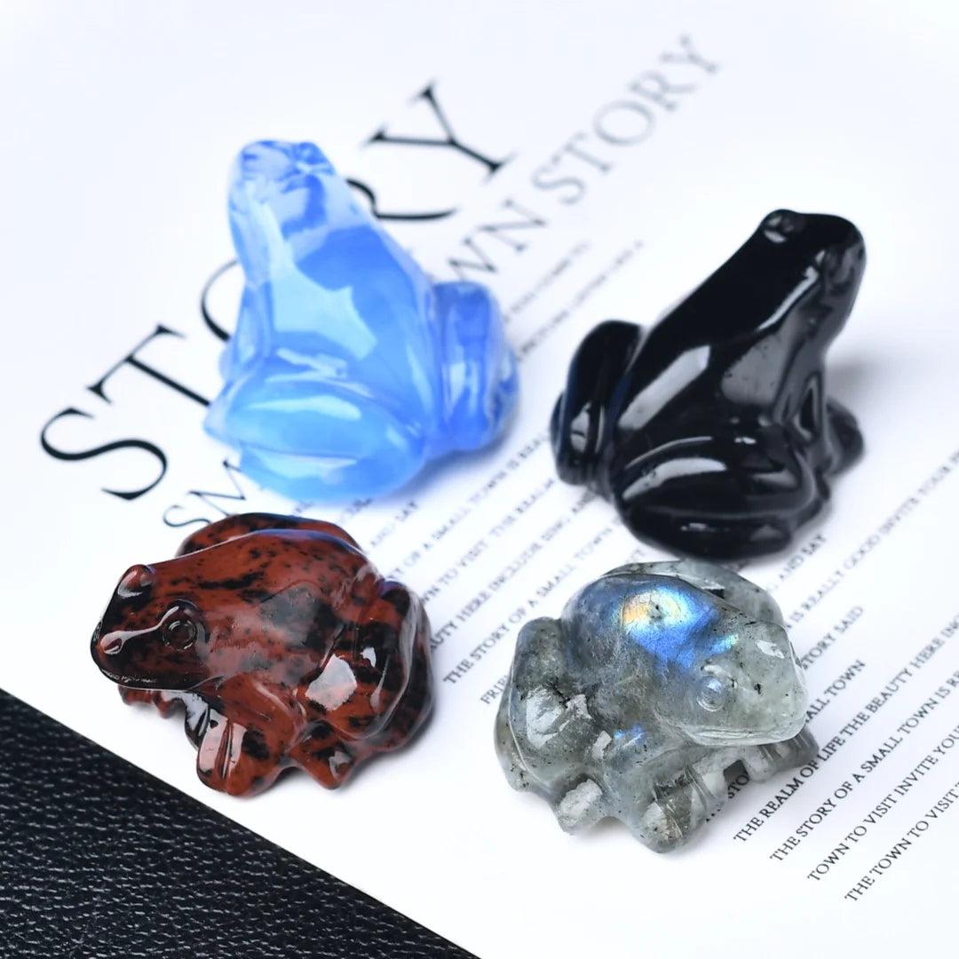 Four Natural Crystal Carved Frog Figurines: Blue Opal, Obsidian, Red Obsidian, and iridescent Labradorite.