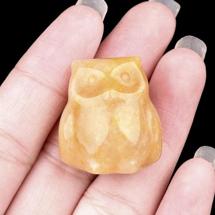 Polished yellow jade mini owl figurine, approximately 25mm, held in a palm, symbolizing wisdom and intuition.