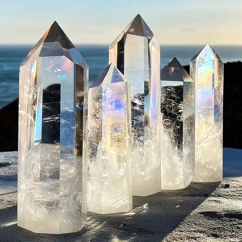 Clear quartz hexagonal obelisk wands with iridescent rainbow refractions, perfect for healing and home decor.