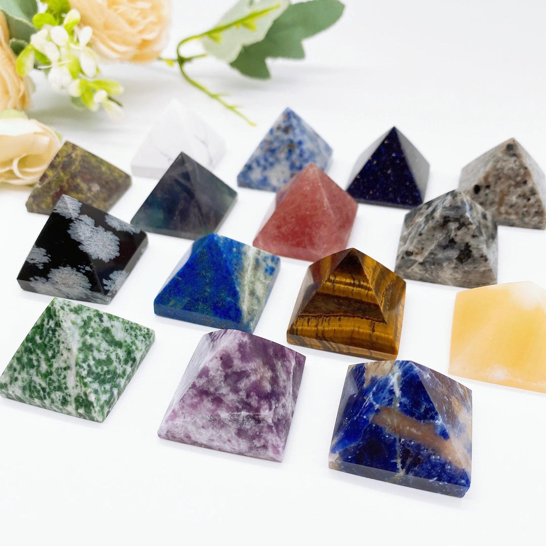Assorted natural crystal pyramid healing stones in various colors like Tiger Eye, Lapis Lazuli, and Fluorite.