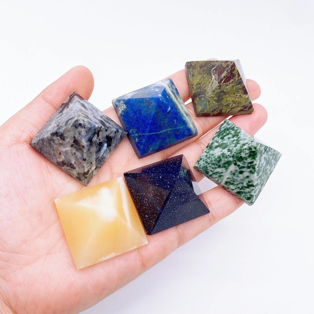 Hand holding a collection of colorful natural crystal point tower pyramids for healing and meditation.