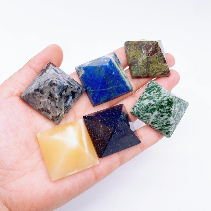 Hand holding a collection of colorful natural crystal point tower pyramids for healing and meditation.
