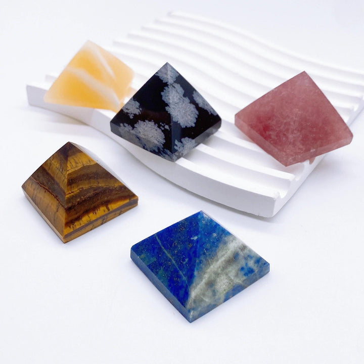 Assorted natural crystal pyramids: golden Tiger Eye, black Snowflake Obsidian, blue Lapis Lazuli, pink, and orange.