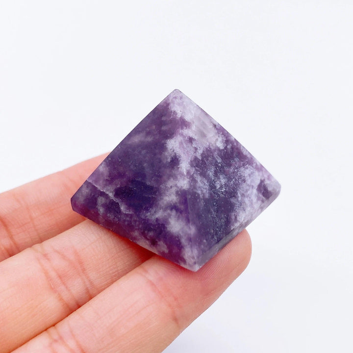 Hand holding a small, 30mm purple Lepidolite crystal pyramid with white veins, ideal for healing and meditation.
