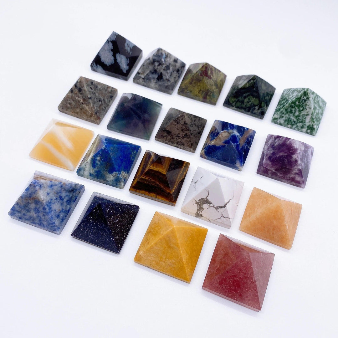 Assorted natural crystal pyramid healing stones in various colors and patterns, including Tiger Eye, Fluorite, and Lapis Lazuli.