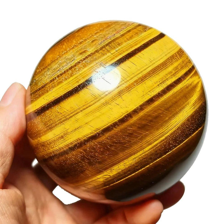 Polished natural Tiger Eye crystal sphere with golden-brown chatoyant bands, perfect for Reiki healing and home decor.