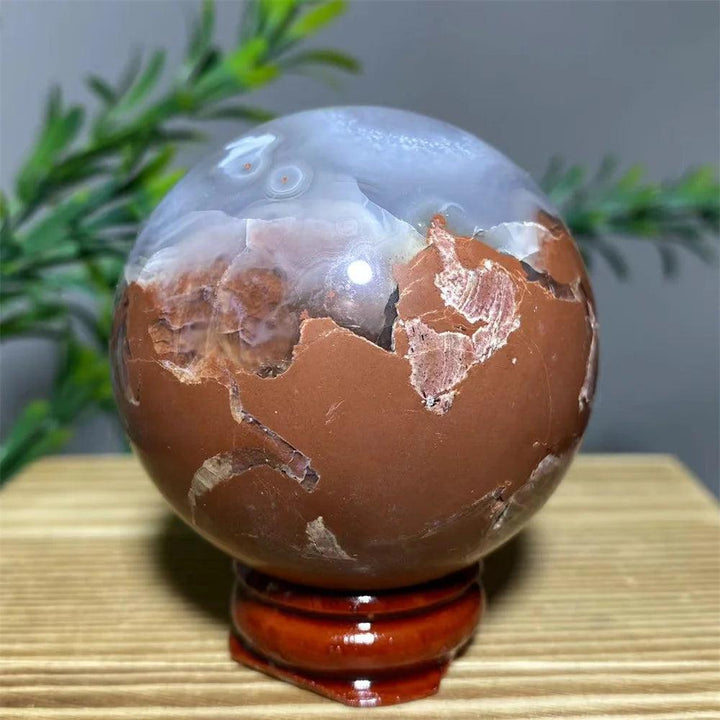 Natural brown and white agate sphere with unique patterns on a wooden stand, for spiritual decoration.