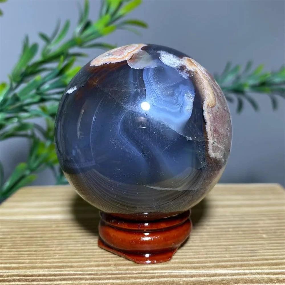 Natural dark blue and brown agate sphere with white flash, on a wooden stand, for spiritual decoration.