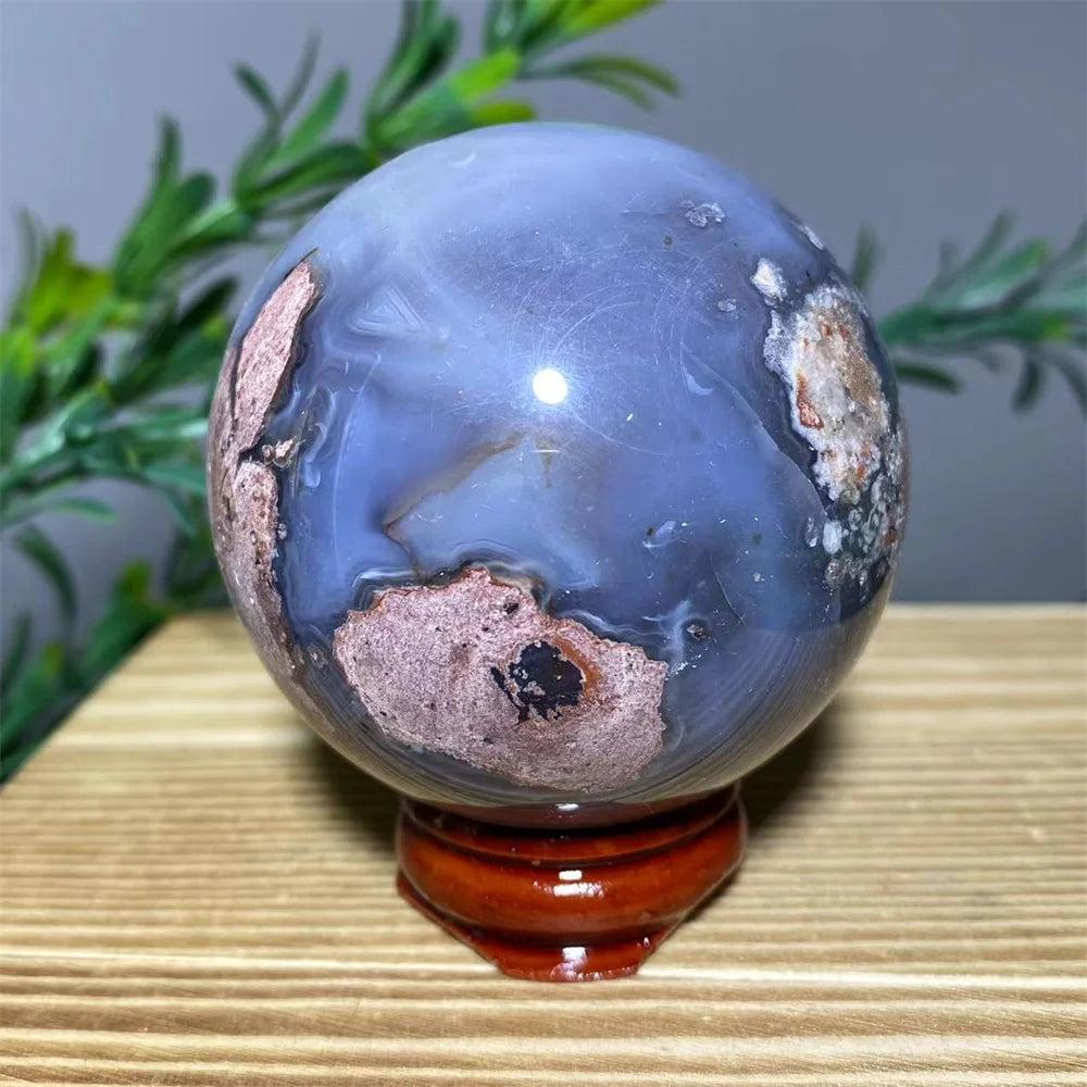 Blue and brown natural agate sphere with flash stone quartz, on a wooden stand, for home decoration.