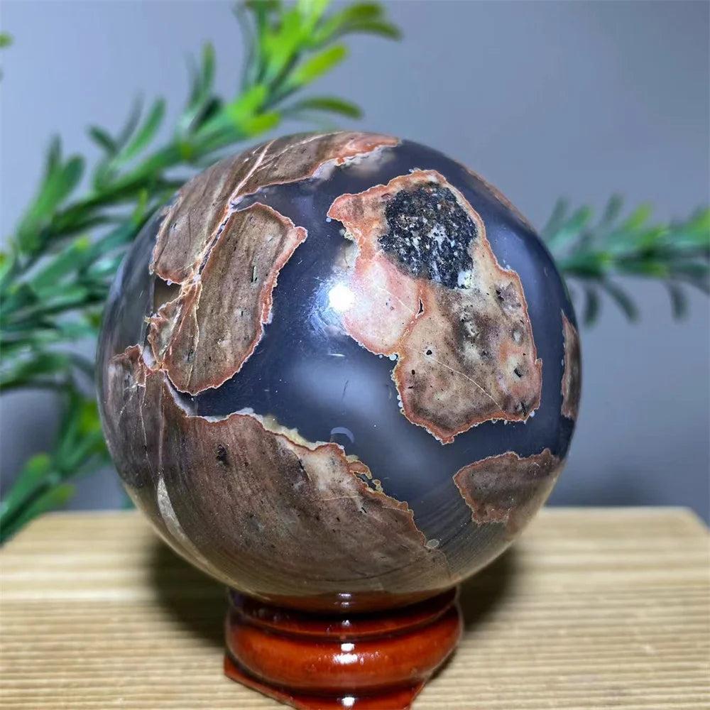 Natural agate sphere with brown, black, and gray patterns on a wooden stand, promoting spiritual healing.