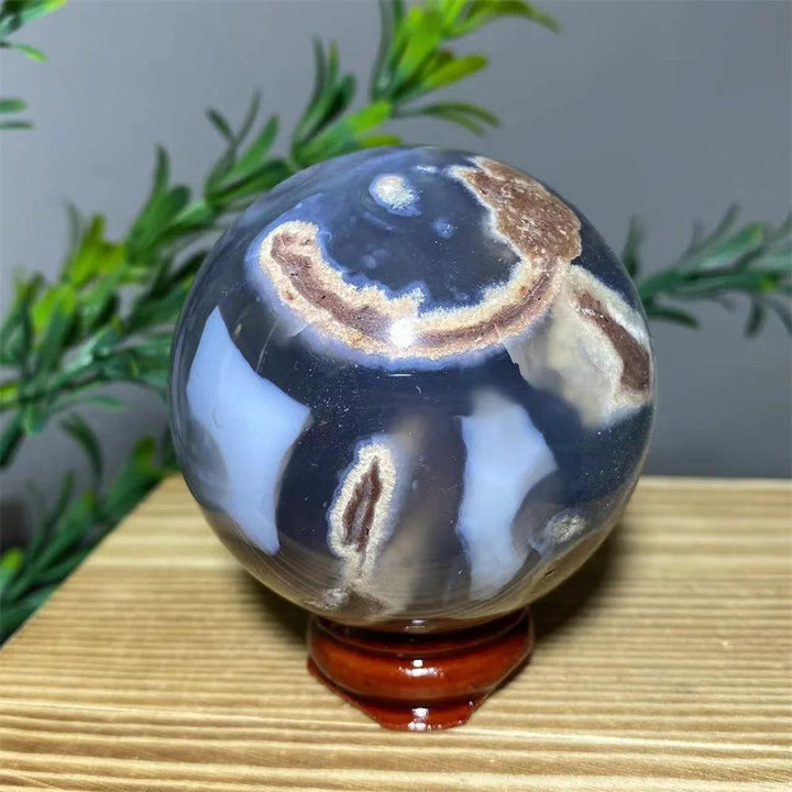 Natural blue and brown agate sphere on a wooden stand, a unique spiritual home decoration.