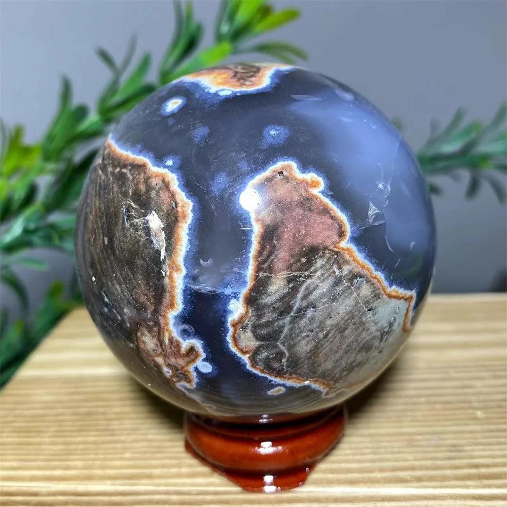 Natural blue agate sphere with brown and orange patterns on a wooden stand.