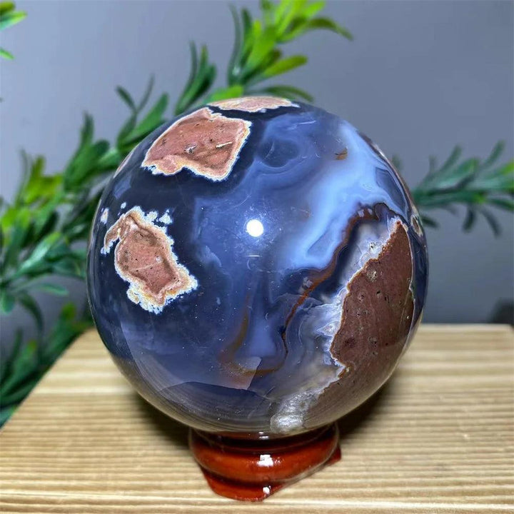 Polished blue and brown agate sphere on a wooden stand, a natural crystal decoration.