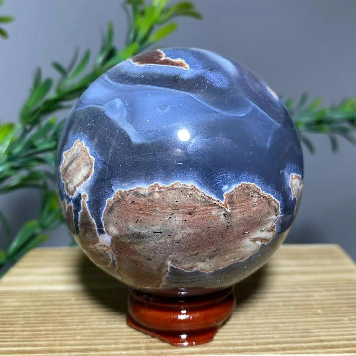 Natural blue and brown agate sphere on a wooden stand, a spiritual home decoration.
