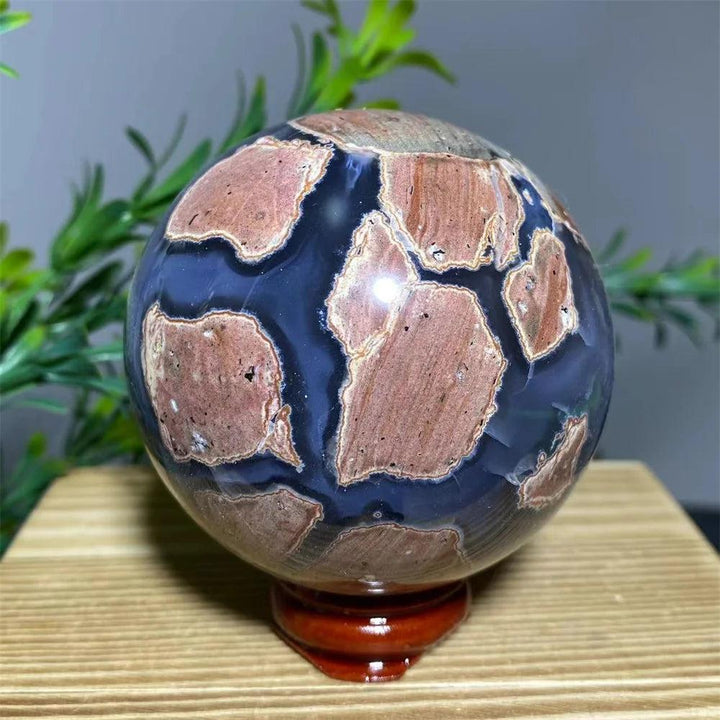 Natural agate sphere with blue and reddish-brown patterns on a wooden stand, ideal for home decoration.