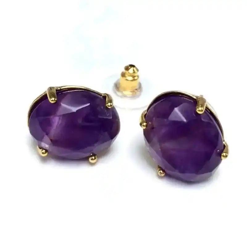 Elegant oval amethyst stud earrings with gold-tone settings, promoting wisdom and clarity.
