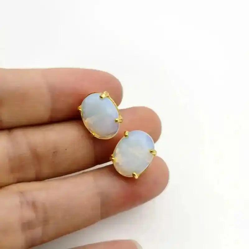 Elegant oval opal stud earrings with gold-tone settings, offering clarity and wisdom.