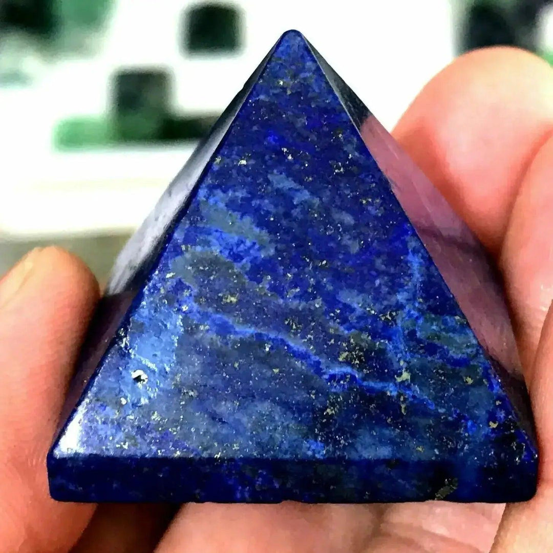 Deep royal blue Lapis Lazuli crystal pyramid with golden pyrite flecks, held in hand, from Crystal Destiny.