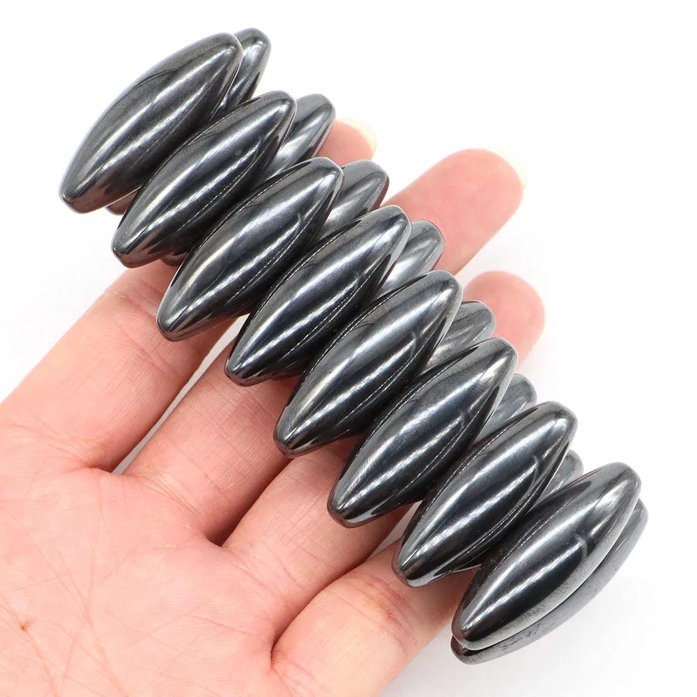 Polished, dark metallic gray natural magnetic hematite olive-shaped beads, 38x13mm, held in a hand.