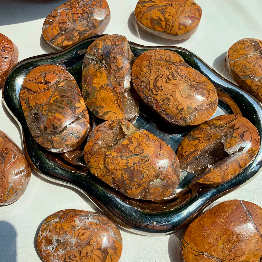 Polished Maligano Jasper palm stones featuring swirling cream, tan, and rust patterns for grounding and meditation.