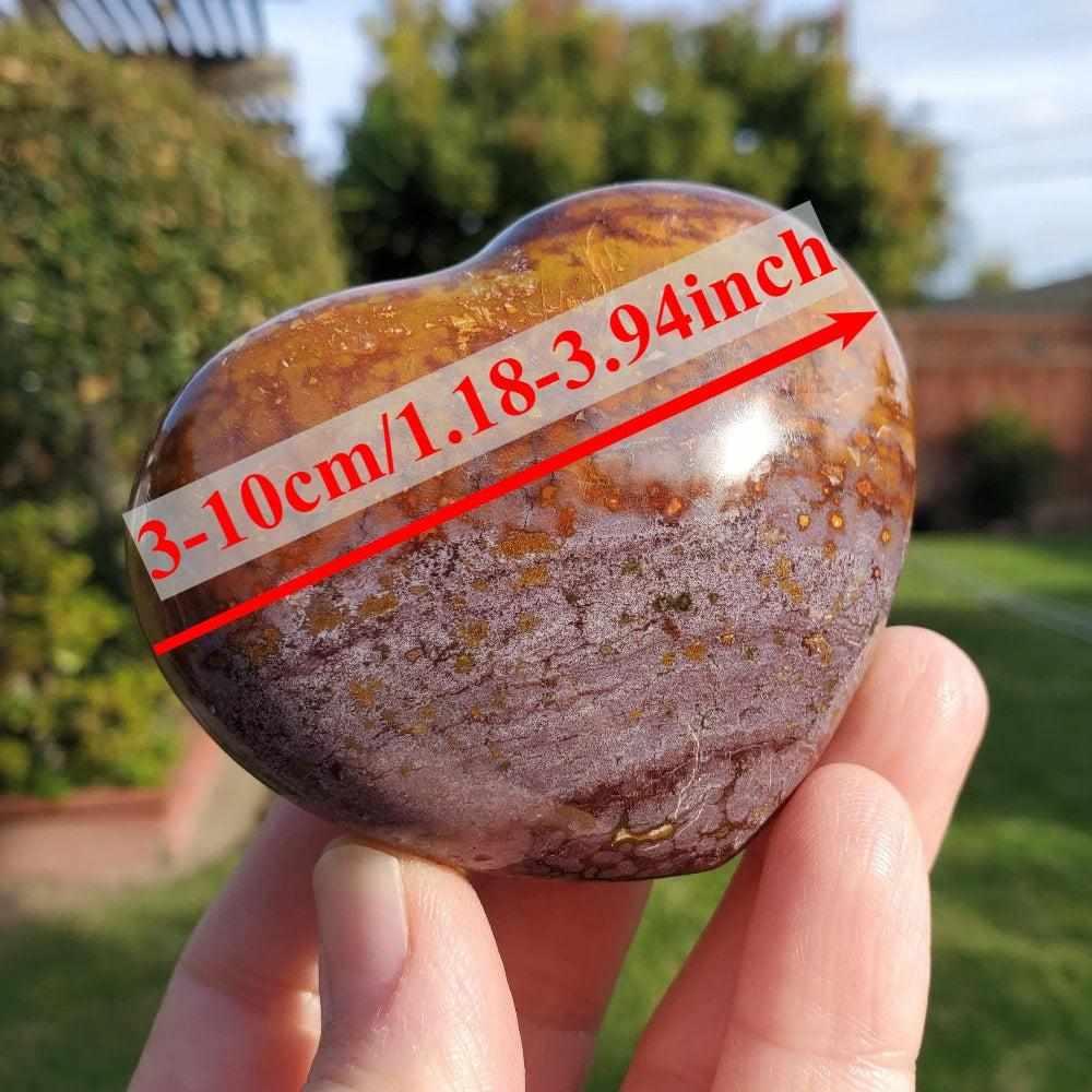 Polished Ocean Jasper heart crystal with orb patterns in green, tan, and purple, held in hand for healing energy.
